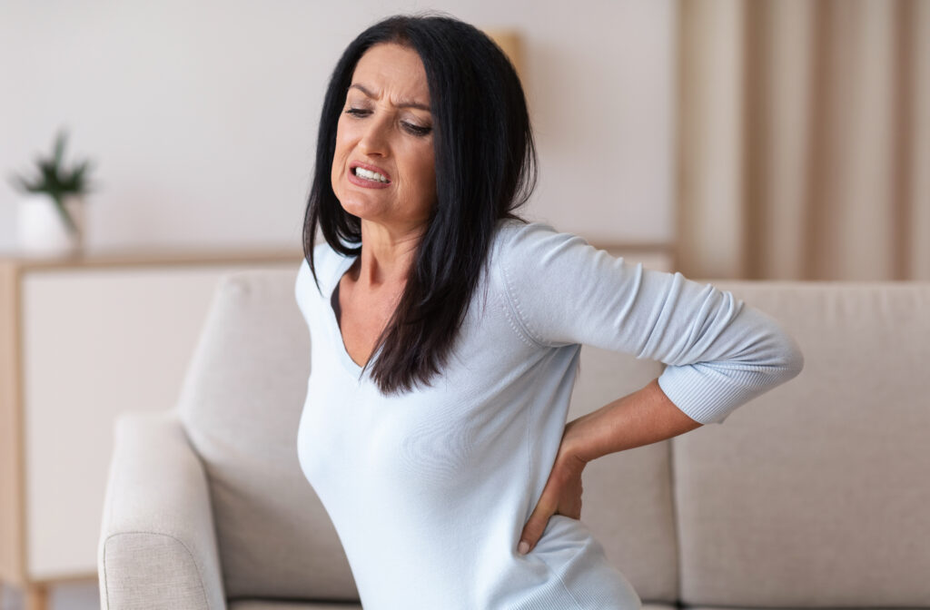 Woman experiencing lower back pain, a common condition treated by an osteopath.